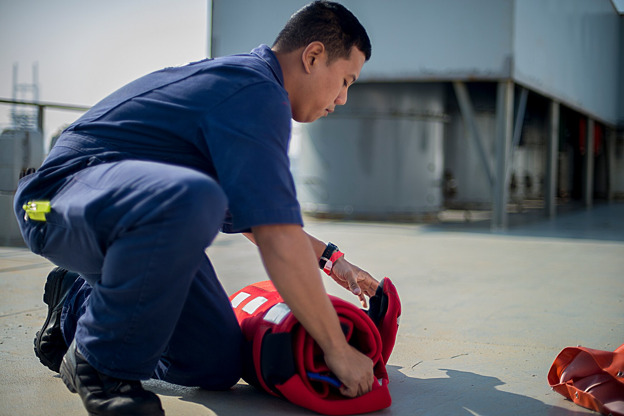 Lt. Kenn Yuen, Coast Guard Activities Far East marine inspector, unrolls an immersion suit during an inspection aboard the U.S. flagged ship GREEN RIDGE at Yokohama, Japan, Dec. 16, 2015. Equipment was inspected to ensure that they met safety standards set by U.S. regulation and international conventions. (U.S. Air Force photo by Senior Airman David C. Danford/Released)