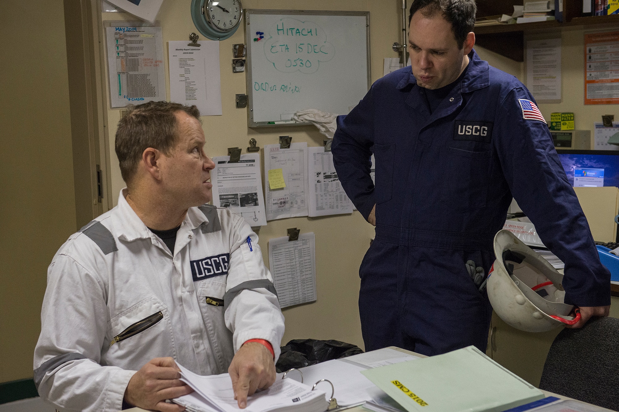 Chief Warrant Officer Robert Moseley, Coast Guard Activities Far East marine inspector, and Lt. Matthew Arnold, FEACT Chief of Investigations, review crew documentation aboard the U.S. flagged ship GREEN RIDGE at Yokohama, Japan, Dec. 16, 2015. Ensuring all of the crews documentation is in order prevents the ship from being detained in foreign ports. (U.S. Air Force photo by Senior Airman David C. Danford/Released)