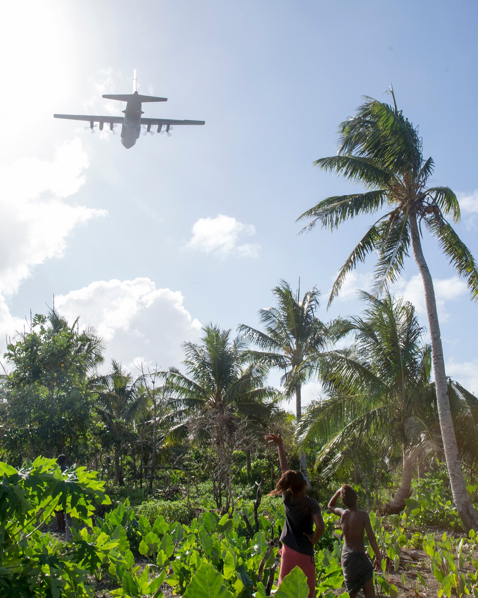 Children from the Fais island waves to a C-130 Hercules fly over head during Operation Christmas Drop at Fais island, Federated States of Micronesia, Dec. 8, 2015. (U.S. Air Force photo by Osakabe Yasuo/Released)
 
