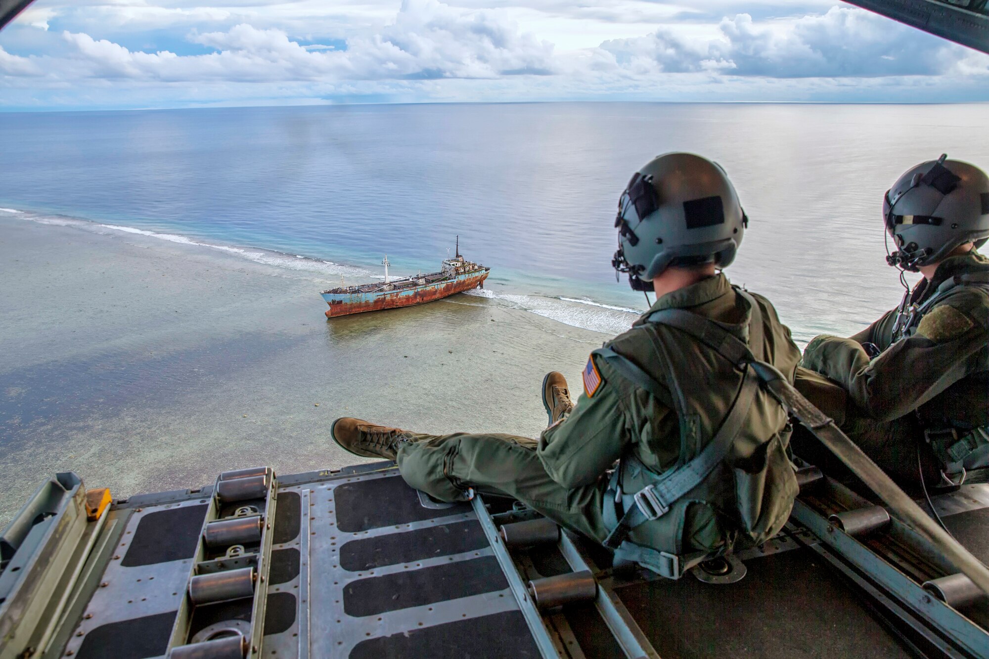 (Right to left) Staff Sgt. Ren Forbes and Airman 1st Class Alexander Lauher, 36th Airlift Squadron loadmasters, look out the back of a C-130H Hercules to the people of the Namoluk Island, Federated States of Micronesia, Dec. 9, 2015, during Operation Christmas Drop. Every December, C-130H Hercules aircrews from Yokota head to Andersen Air Force Base to execute low-cost, low-altitude humanitarian airdrops to islanders throughout the Commonwealth of the Northern Marianas, Federated States of Micronesia, Republic of Palau. These islands are some of the most remote locations on the globe spanning a distance nearly as broad as the continental U.S. It is the longest-running Department of Defense humanitarian airdrop operation with 2015 being the first trilateral execution with support from Japan Air Self-Defense Force and Royal Australian Air Force. (U.S. Air Force photo by Osakabe Yasuo/Released)
