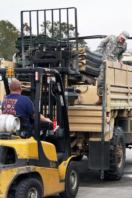 A Louisiana National Guardsman and local officials load HESCO barriers onto a light medium tactical vehicle to be used for building a 12,550-foot long levee on Avoca Island in St. Mary Parish in advance of expected river flooding in Morgan City, La., Jan. 8, 2016. The Louisiana National Guard mobilized more than 250 personnel in an effort to build protective barriers against the approaching flood waters and to patrol levees. Louisiana Army National Guard photo by Spc. Garrett Dipuma