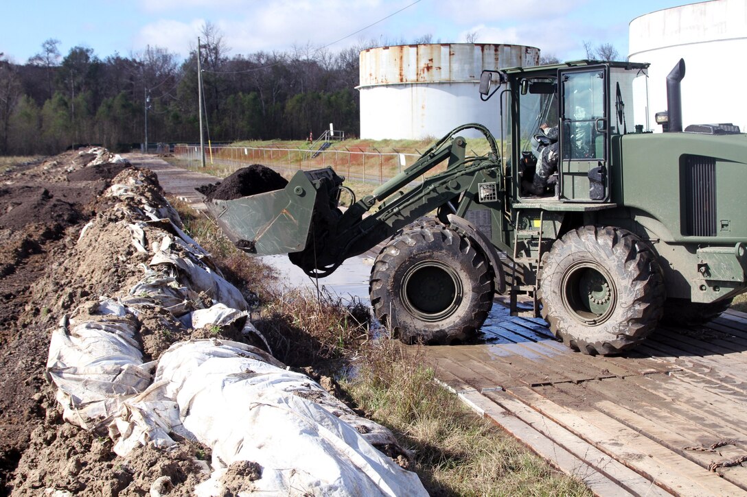 A soldier operates heavy equipment to repair and build a flood barrier in support of Operation Winter River Flooding, Jan. 9, 2016. Louisiana Army National Guard photo by Spc. Tarell J. Bilbo