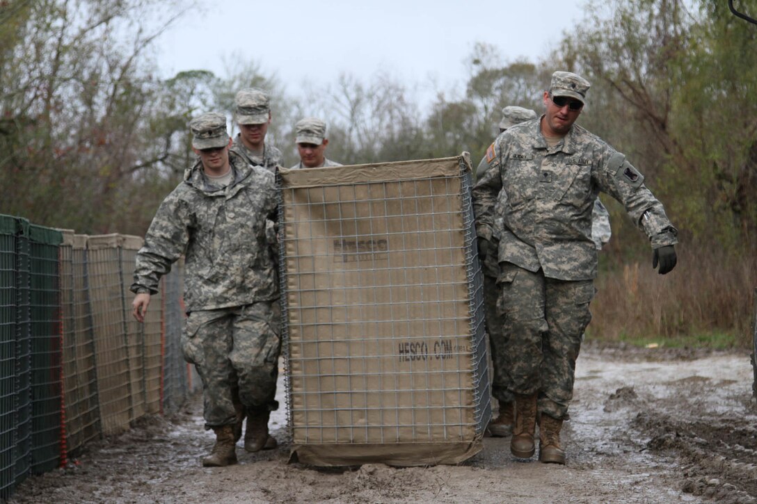 Army Spcs. Scott Mouton, left, and Mason Guidry and other soldiers carry a HESCO barrier on Avoca Island in advance of expected river flooding in Morgan City, La., Jan. 9, 2016. The soldiers are assigned to the Louisiana National Guard’s 2225th Multi-Role Bridge Company, 205th Engineer Battalion, 225th Engineer Brigade. The barrier will be used in the construction of a 2-mile-long levee to prevent backwater flooding from reaching Morgan City and other towns in southern Louisiana due to high river levels. Louisiana Army National Guard photo by Spc. Garrett Dipuma