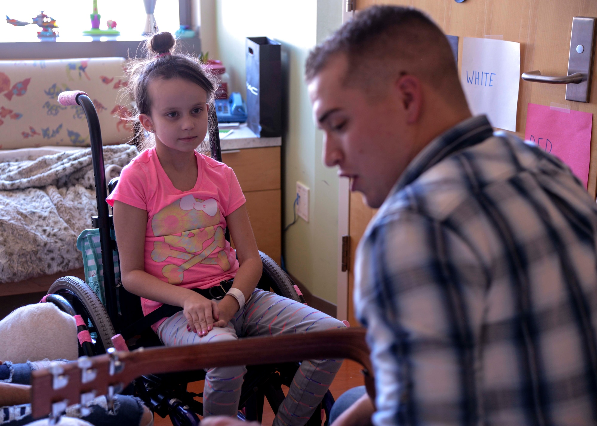 Kimmy Duran, patient of the Children's Hospital Colorado in Aurora, Colorado, watches as Airman 1st Class Dylan Westmoreland, 790th Quick Response Force, plays music for her, Jan. 6, 2016. Duran is one of several children Westmoreland was able to play for after his broadcast throughout the whole hospital. (U.S. Air Force photo by Airman 1st Class Malcolm Mayfield)