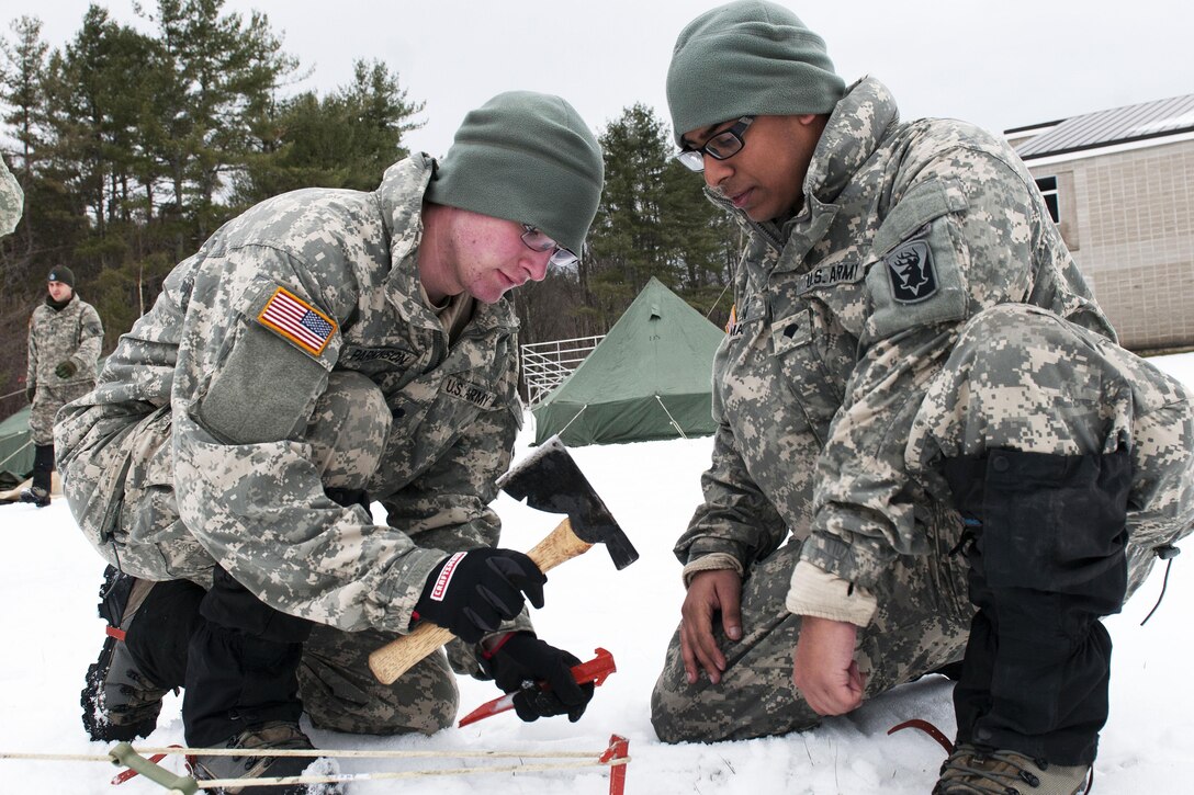 Army Spc. Peter Parkinson, left, hammers in stakes while another soldier looks on during training at Camp Ethan Allen Training Site in Jericho, Vt., Jan. 9, 2016. Parkinson is an infantryman assigned to the Vermont Army National Guard’s Company A, 3rd Battalion, 172nd Infantry Regiment, Mountain. Vermont Army National Guard photo by Spc. Avery Cunningham