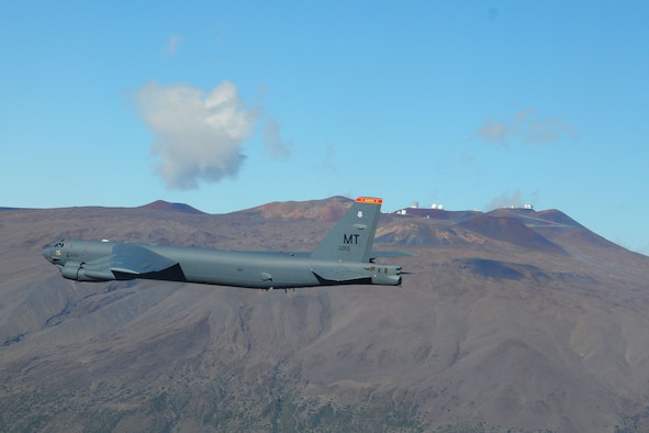 With the Mauna Kea volcano in the background, a B-52 Stratofortress from the 23rd Expeditionary Bomb Squadron, flies over the Mauna Loa volcano, Hawaii, on Dec. 28, 2015, during a training mission. Two B-52 aircrews currently assigned here as part of the U.S. Pacific Command's continuous bomber presence, conducted a bomber Airmen heritage flyby of the Mauna Loa volcano. The flyby was part of the 80th anniversary of the 23rd Bombardment Squadron using bombs to divert lava flow from the volcano that threatened the town of Hilo, Hawaii, in 1935. (Courtesy photo)
