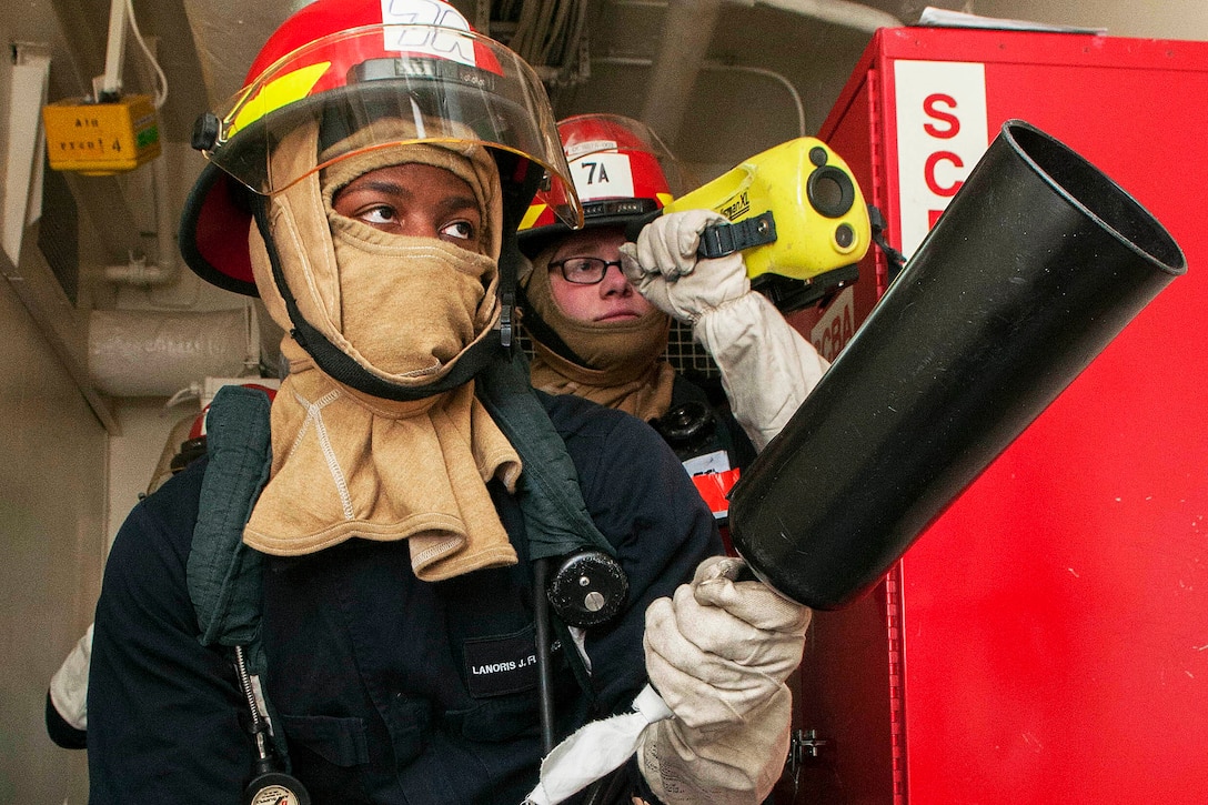 Navy Petty Officer 3rd Class Lanoris Florence, right, and Airman Nathan McCoy simulate fighting an electrical fire on the aircraft carrier USS Ronald Reagan in Yokosuka, Japan, Jan. 9, 2016. The carrier provides a combat-ready force to protect the collective maritime interestes of its allies and partners in the Indo-Asia Pacific Region. U.S. Navy photo by Seaman MacAdam Kane Weissman