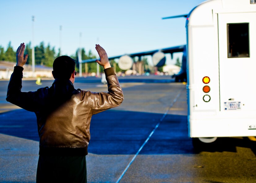 A member of the 46th Aeromedical Evacuation Squadron,  waves a bus full of  patients behind a C-17 Globemaster during a monthly patient load exercise at Joint Base Lewis-McChord, Wash., Jan. 10. The 446th Aeromedical Staging Squadron performed a patient load exercise to practice loading critically wounded members onto the C-17 for evacuation. The ASTS works closely with the 446th AES to accomplish the mission of loading patients and caring for them in flight. (U.S. Air Force Reserve photo by Staff Sgt. Daniel Liddicoet)