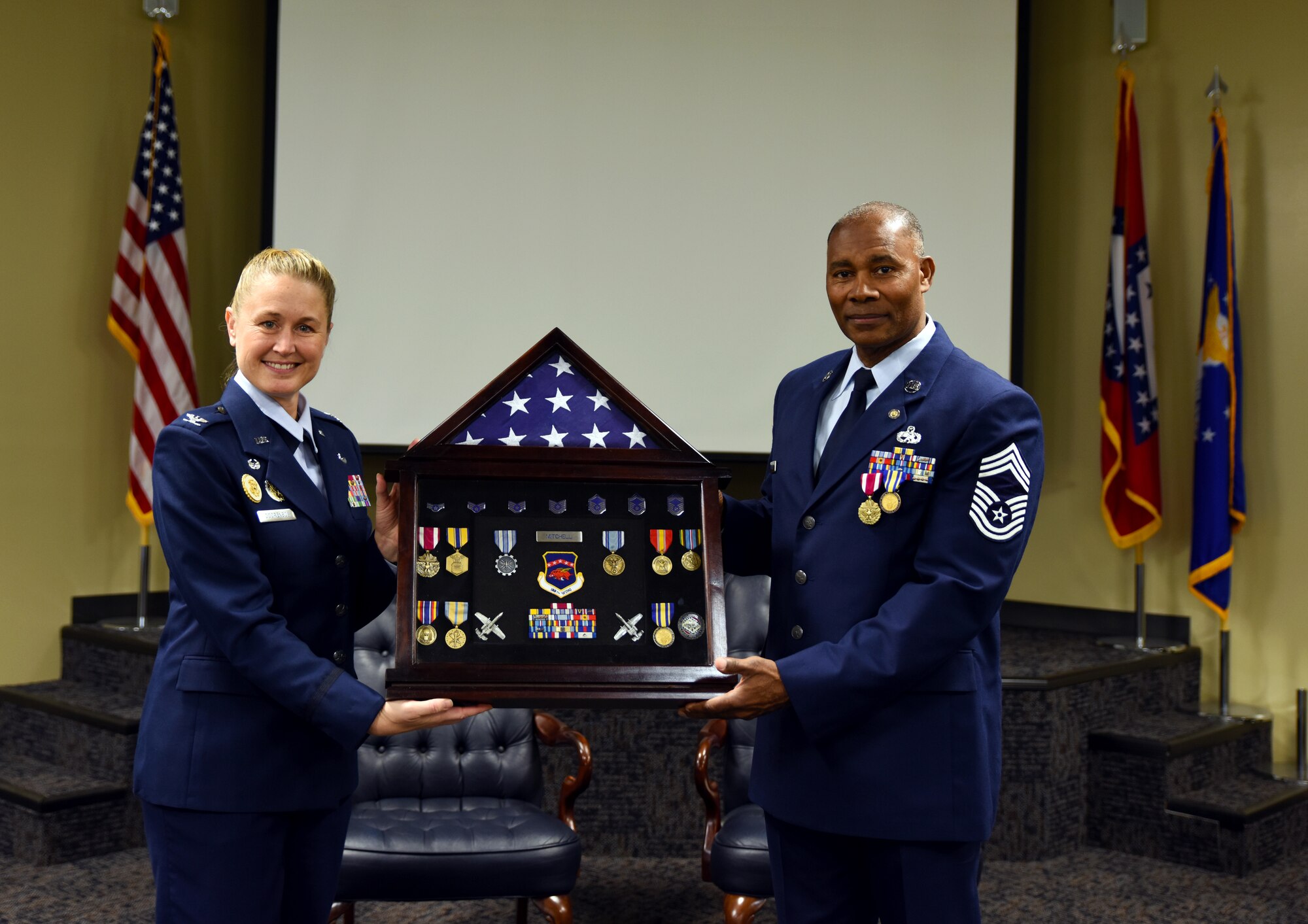 Chief Master Sgt. Kerry Mitchell, 188th Wing human resource advisor, receives a shadowbox Jan. 10, 2016, from Col. Bobbi Doorenbos, 188th Wing commander, during his retirement ceremony at Ebbing Air National Guard Base, Fort Smith, Ark. Mitchell served in the Air National Guard for more than 31 years and previously worked as the first sergeant for the 188th Maintenance Squadron and as the supervisor of the 188th non-destructive inspection shop before becoming the wing human resource advisor. (U.S. Air National Guard photo by Senior Airman Cody Martin/Released)