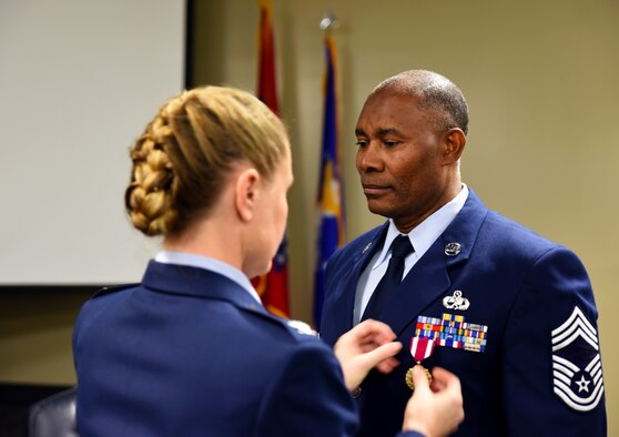 Chief Master Sgt. Kerry Mitchell, 188th Wing human resource advisor, is pinned the Meritorious Service Medal Jan. 10, 2016, by Col. Bobbi Doorenbos, 188th Wing commander, during his retirement ceremony at Ebbing Air National Guard Base, Fort Smith, Ark. Mitchell served in the Air National Guard for more than 31 years and previously worked as the first sergeant for the 188th Maintenance Squadron and as the supervisor of the 188th non-destructive inspection shop before becoming the wing human resource advisor. (U.S. Air National Guard photo by Senior Airman Cody Martin/Released)