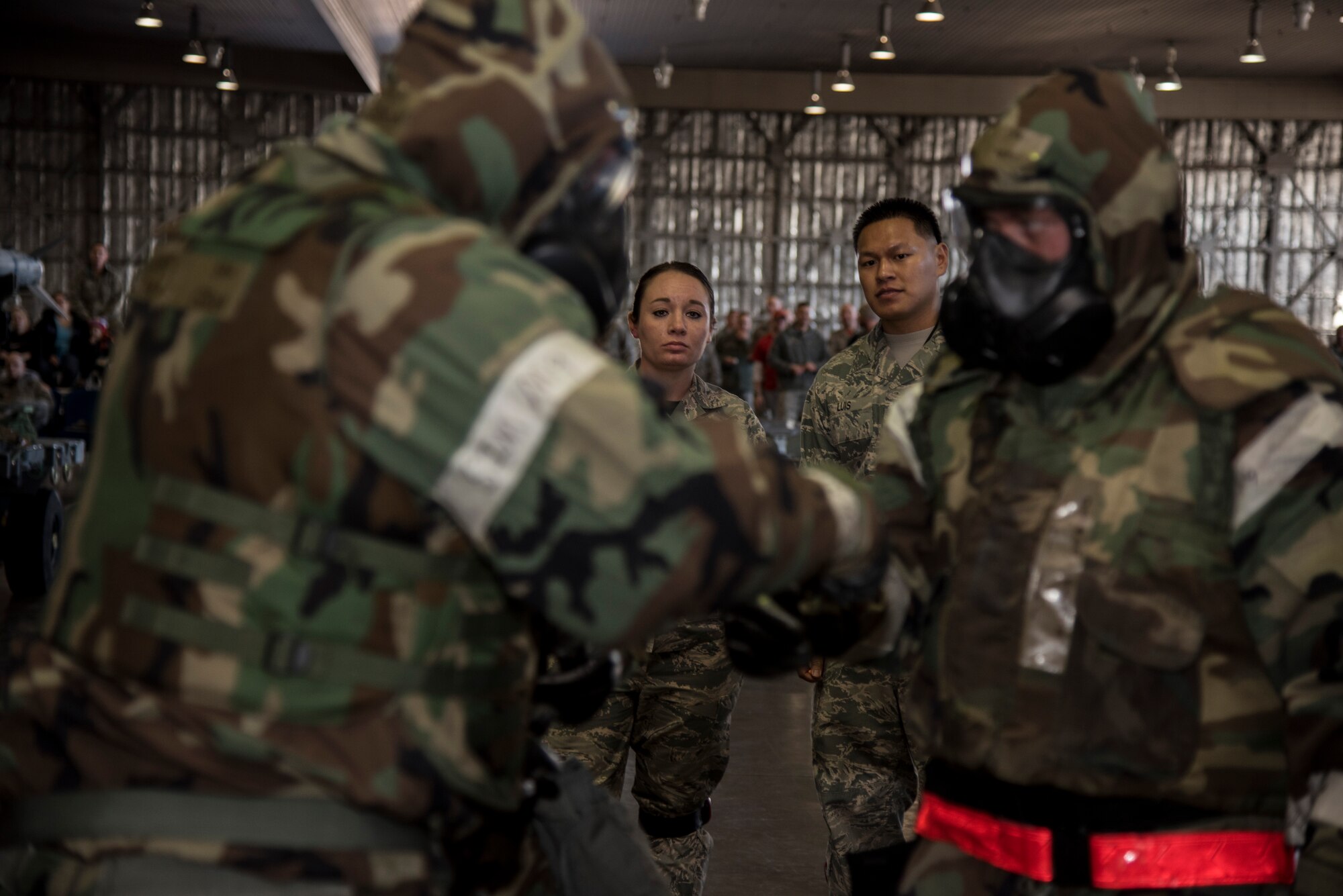 U.S. Air Force Senior Airman Kaitlyn McKenzie, a weapons standardization lead crew member, and Tech. Sgt. Gregorio Luis, weapons standardization load standardization crew member, both with the 35th Maintenance Group, watch load crew Airmen with the 35th Aircraft maintenance Squadron, 13th Aircraft Maintenance Unit, perform a buddy check on their mission-oriented protective posture gear during the annual Maintenance Professional of the Year load crew competition at Misawa Air Base, Japan, Jan. 8, 2016. Each of the teams being graded were given a set number of points and then were docked for any discrepancies the weapons standardization Airmen observed. (U.S. Air Force photo by Senior Airman Brittany A. Chase)
