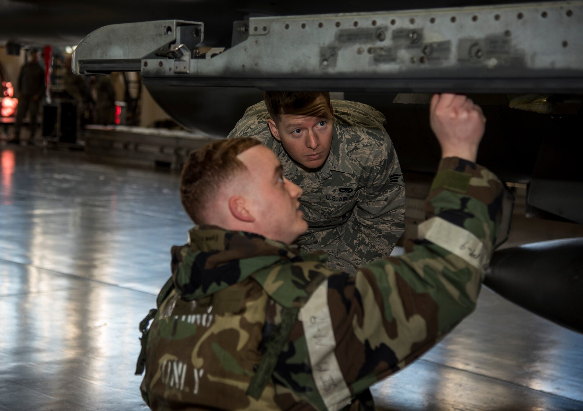 U.S Air Force Senior Airman David Pickett, a weapons standardization lead crew member with the 35th Maintenance Group, observes Senior Airman Donald Ramsey, a load crew member with 35th Aircraft maintenance Squadron, 13th Aircraft Maintenance Unit, as he prepares to load a weapons system during the annual Maintenance Professional of the Year load crew competition at Misawa Air Base, Japan, Jan. 8, 2016. Pickett’s job was to ensure the Airmen were safely and properly loading munitions. Each of the teams being graded were given a set number of points and then docked for any discrepancies the weapons standardization Airmen observed. (U.S. Air Force photo by Senior Airman Brittany A. Chase)