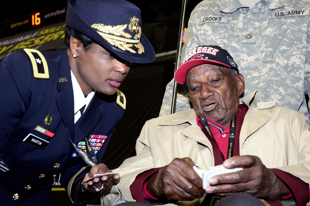 Army Brig. Gen. Donna Martin, left, deputy commander, U.S. Army Recruiting Command, listens to stories and looks at pictures from Theodore Johnson, one of few surviving Tuskegee airmen, during the pre-game ceremonies of the 2016 All-American Bowl in San Antonio, Texas, Jan. 9, 2016. Johnson was introduced to a loud ovation at the 50-yard line prior to the opening kickoff. U.S. Army photo by Sgt. 1st Class Rauel Tirado