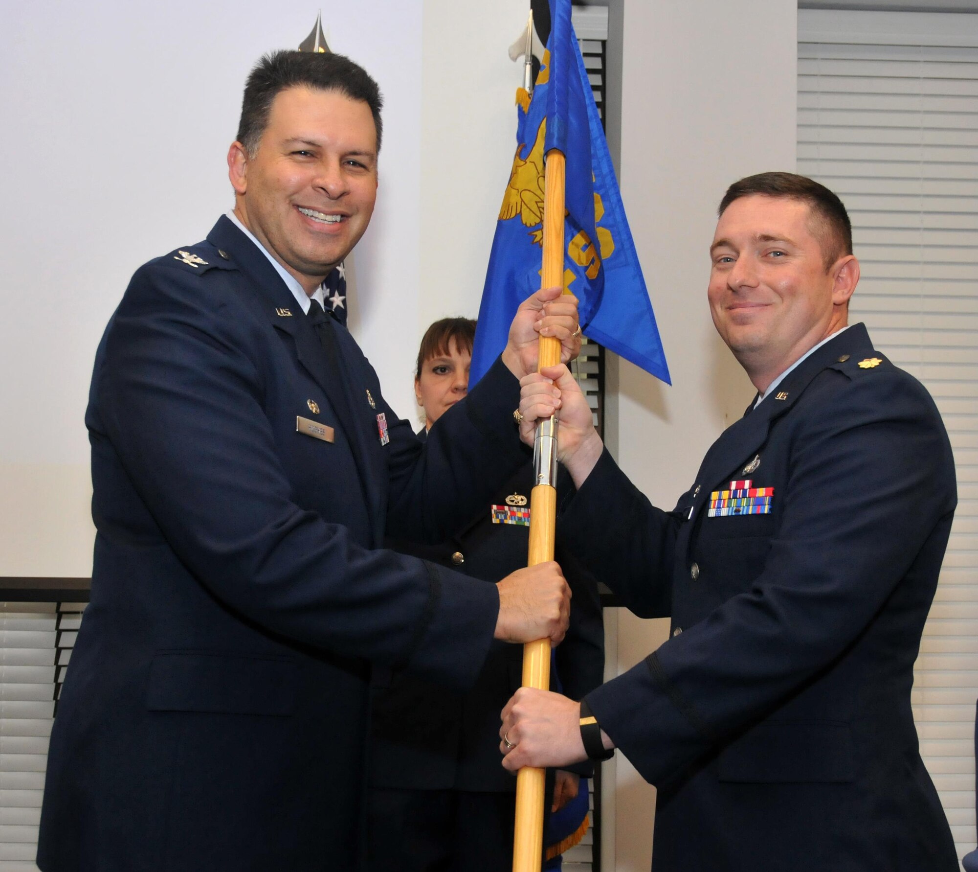 Maj. Wallace Collins receives the 94th Force Support Squadron flag from Col. Marty Hughes, 94th Maintenance Support Group commander, marking the assumption of command for the 94th FSS on Jan. 10, 2016 in Verhulst Hall at Dobbins Air Reserve Base, Ga. (U.S. Air Force photo/ Senior Airman Andrew J. Park)