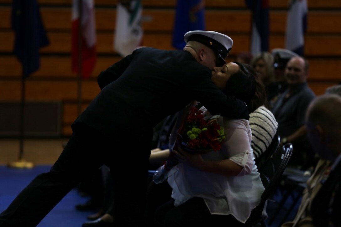 Master Chief Petty Officer Robert Lemons (center), the command master chief of the 1st Marine Division, presents his wife with a bouquet of flowers during his retirement ceremony aboard Marine Corps Base Camp Pendleton, Calif., Jan. 8, 2016. Lemons enlisted in the U.S. Navy in 1986 and served a majority of his time in the service as a corpsman.