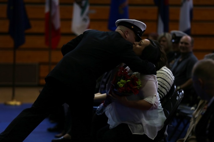 Master Chief Petty Officer Robert Lemons (center), the command master chief of the 1st Marine Division, presents his wife with a bouquet of flowers during his retirement ceremony aboard Marine Corps Base Camp Pendleton, Calif., Jan. 8, 2016. Lemons enlisted in the U.S. Navy in 1986 and served a majority of his time in the service as a corpsman.