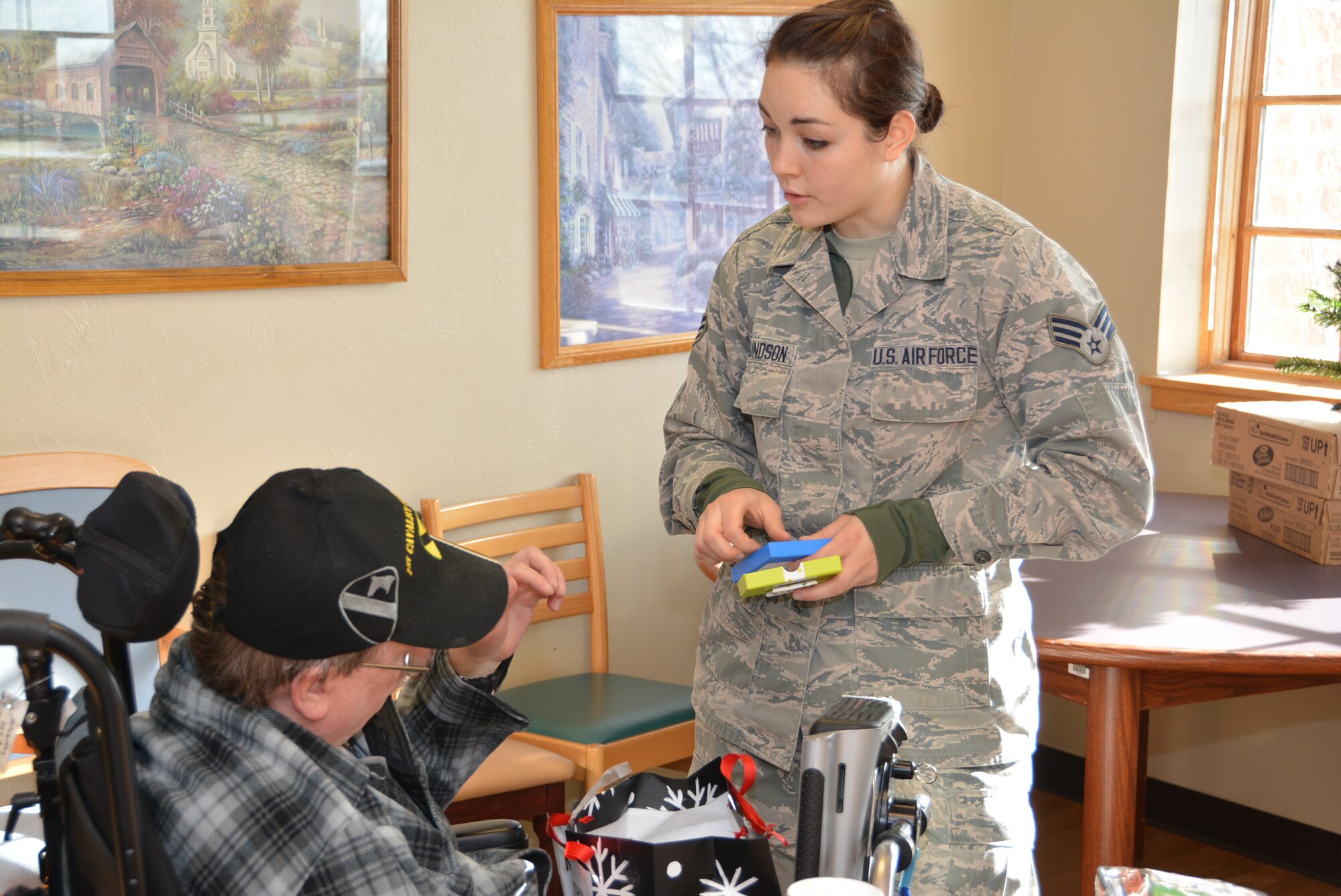 Senior Airman Talisa Edmundson of the 507th Civil Engineer Squadron, Tinker Air Force Base, Okla., assists a Veteran while opening a gift Dec. 22, 2015, at the annual Norman Veterans Center Angel Tree party in Norman, Okla. Through the Angel Tree program, 25 volunteers delivered gifts to 20 Veterans and nearly $700 collected from the 507th ARW, the 1st Aviation Standards flight, and the 513th Air Control Group.  (U.S. Air Force photo/Maj. Jon Quinlan)