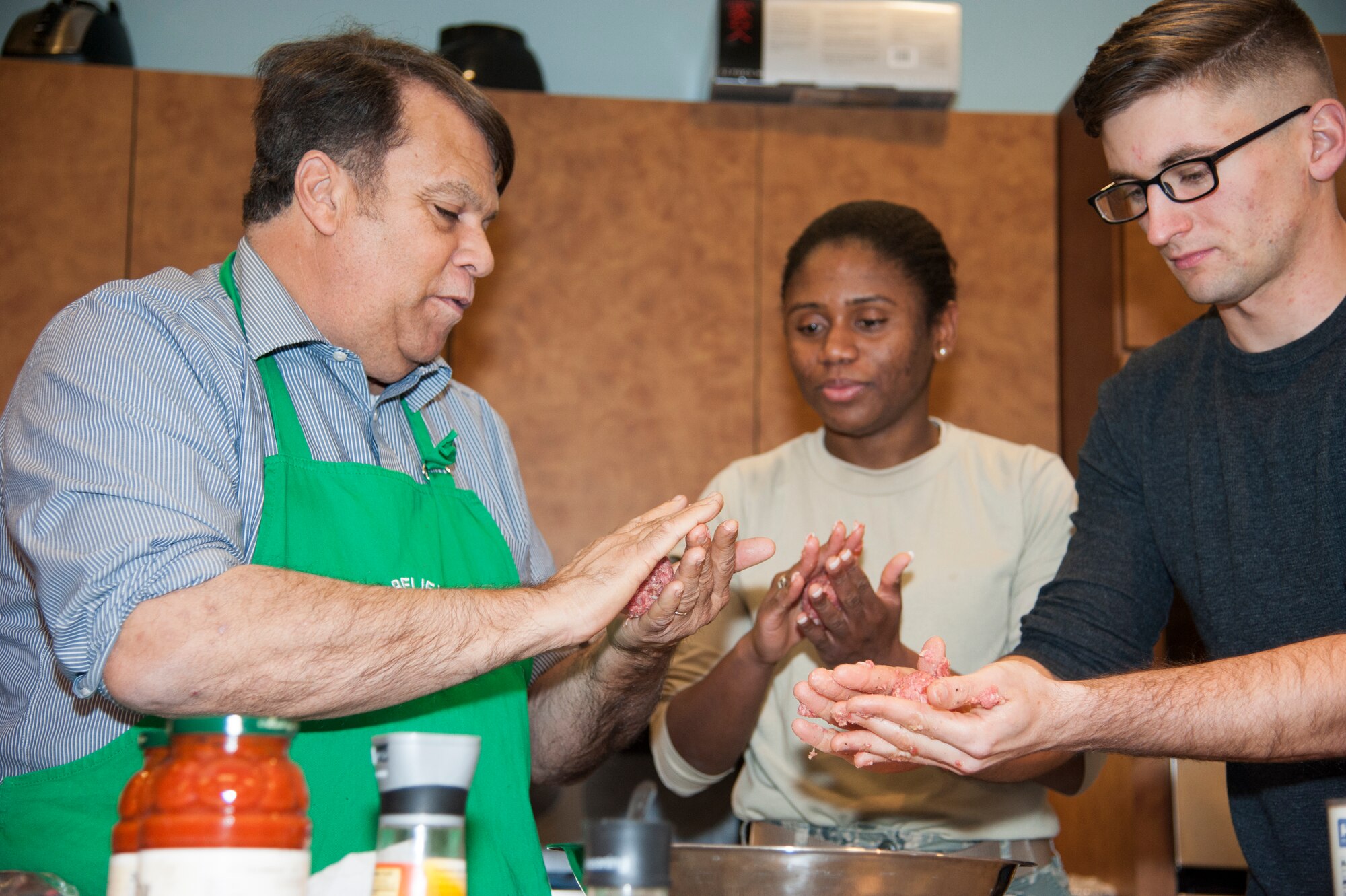 Robin Christiansen, Mayor of Dover, talks with Airman 1st Class Monique Lozano, 436th Aerial Port Squadron traffic management office, and Airman Louis Lotfy, 436th APS aerial porter, about the ingredients of the meatballs during Dorm to Gourm Jan. 5, 2016, at the Health Promotion Flight kitchen in the Fitness Center on Dover Air Force Base, Del. The purpose of the course is to teach Airmen, who live in the dorms, how to cook healthy meals. (U.S. Air Force photo/Staff Sgt. Jared Duhon) 