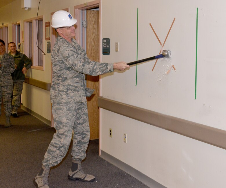 Col. Jeffrey White, 377th Medical Group commander, swings at sledgehammer at a wall during a wall breaking ceremony Jan. 12 to signify the start of major construction to the Medical Clinic. The facility will undergo major renovations in a $16.9 million project. (Photo by Dennis Carlson)