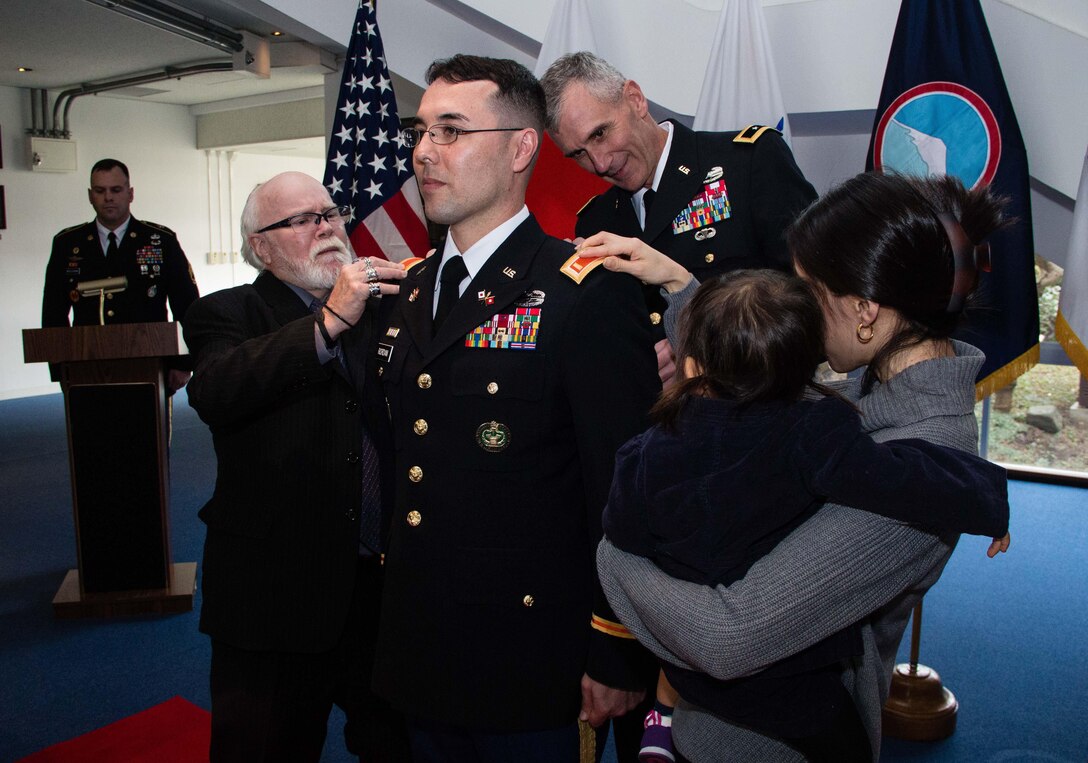 Newly promoted Army 2nd Lt. Riki R. Riordan, signal officer, 311th Signal Command, stands at attention as his father, Patrick (left),and his wife, Miyuki (right), pin second lieutenant bars on their son and husband's shoulders during a direct commission ceremony conducted Jan. 6, 2016, at Camp Zama, Japan. Army Maj Gen. James F. Pasquarette (center, behind Riordan), commanding general, U.S. Army Japan, presided over this unique ceremony only offered to enlisted Soldiers seeking a commission in the U.S. Army Reserve. Born and raised in Tokyo, Riordan enlisted in the Army in 2001 and served as a cavalry scout. Riordan transitioned to the Army Reserve in 2003 and continued to serve his country as a drill sergeant and, later, as a Contingency Acquisition Support Model subject matter expert for U.S. Army Japan. I (U.S. Army photo by Army Sgt. John L. Carkeet IV, U.S. Army Japan)