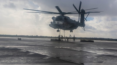 A CH-53E from Marine Heavy Helicopter Squadron (HMH) 465 hovers above as Marines with Combat Logistic Battalion (CLB) 11 rush in to attach 6,200-pound weight to the helicopter aboard Marine Corps Air Station Miramar, Calif., Jan. 7. Marines with CLB-11 support HMH-465 during daytime external lift training to prepare for future deployments. (U.S. Marine Corps photo by Lance Cpl. Harley Robinson/Released)