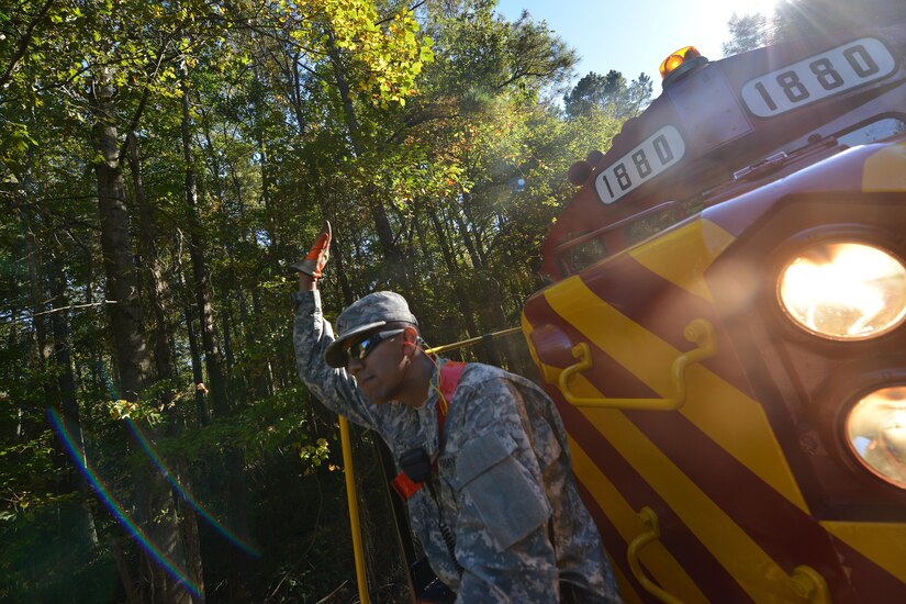U.S. Army Reserve Pvt. Alexis Colin, a railway operations student with the Maritime Intermodal Training Department, signals to the driver that the track is clear at Fort Eustis, Va., Oct. 30, 2015. When operating the train, the students rotated conductor duties, including coupling train cars and surveying the area for hazards. (U.S. Air Force photo by Staff Sgt. Natasha Stannard)
