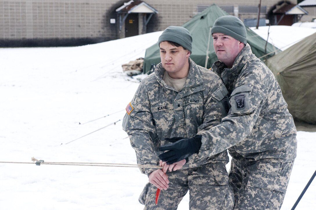 Army Sergeant Jeff Deslauriers, right, shows an officer candidate how to properly line up a tent's main line as part of the company's military mountaineering training at Camp Ethan Allen Training Site, Jericho, Vt., Jan. 9, 2016. Deslauriers is an infantryman assigned to the Vermont Army National Guard’s Company A, 3rd Battalion, 172nd Infantry Regiment, Mountain. Vermont Army National Guard photo by Sgt. Heidi Kroll