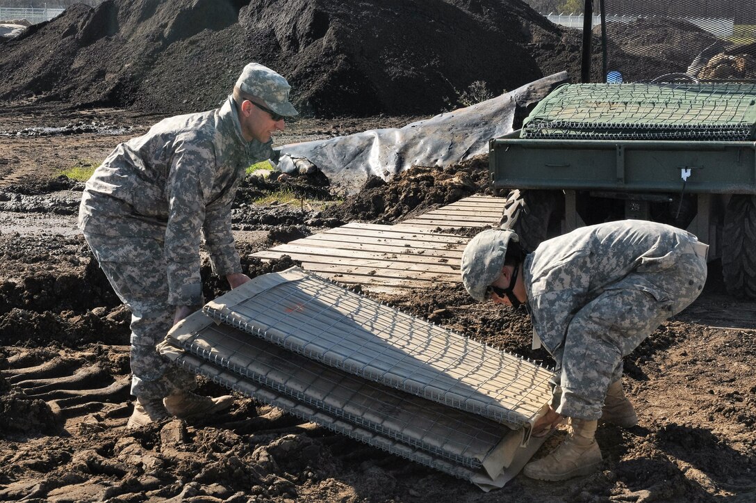Soldiers lift wire-mesh barriers to build a levee to support Operation Winter River Flooding in Krotz Springs, La., Jan. 10, 2016. U.S. Army National Guard photo by Staff Sgt. Greg Stevens