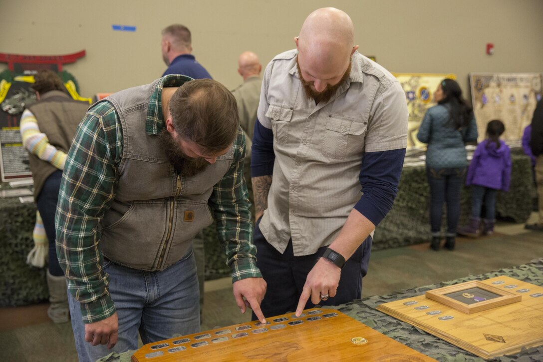 Kirk McPheron and Dan Hickey, 2nd Battalion, 7th Marine Regiment, alumni, look at plaques made in remembrance of their fallen comrades at the battalion’s 75th anniversary at building 1707, Jan. 8, 2016. (Official Marine Corps photo by Lance Cpl. Levi Schultz/Released)