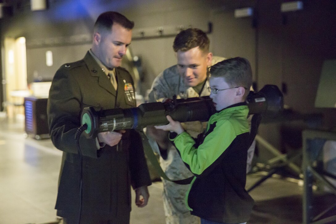 Lt. Col. Christopher Steele, battalion commander, 2nd Battalion, 7th Marine Regiment, helps his son, Luke Steele, 12, fire an 84mm unguided, portable, single-shot, recoilless, smoothbore weapon (AT-4), in the Indoor Simulated Marksmanship Trainer at building 1707, Jan. 8, 2016. (Official Marine Corps photo by Lance Cpl. Levi Schultz/Released)
