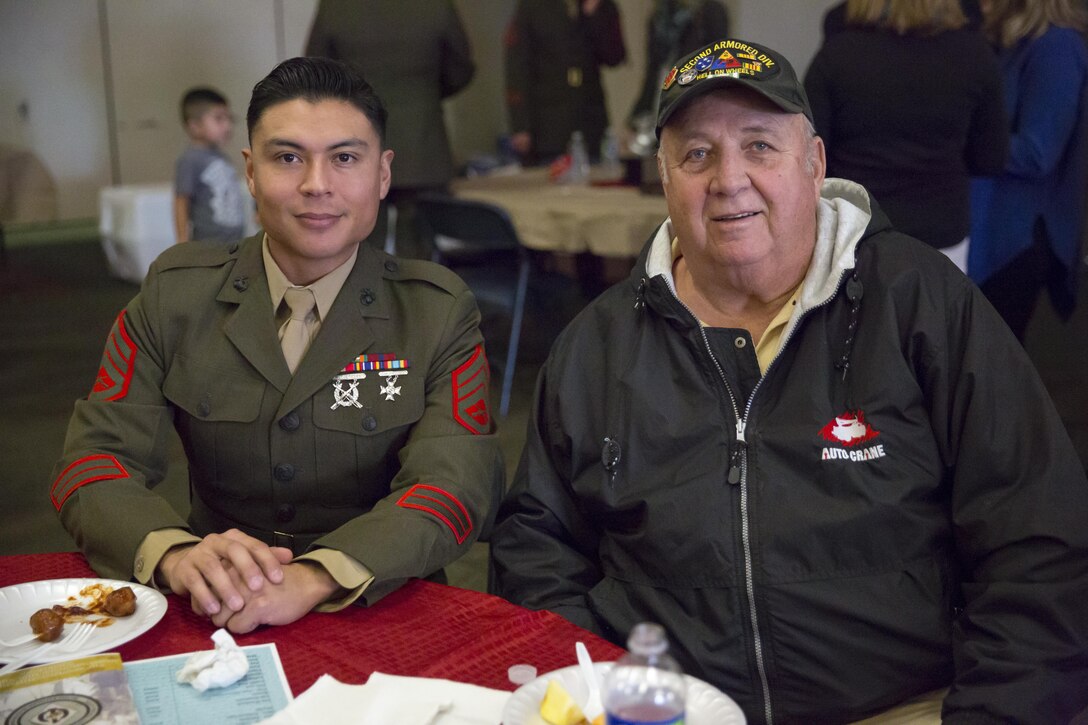 Staff Sgt. Charles Sandoval, career planner, 2nd Battalion, 7th Marine Regiment, and Tom Cobb, 2/7 alumni, discuss their experiences with the battalion during 2/7’s 75th anniversary at building 1707, Jan. 9, 2016. (Official Marine Corps photo by Lance Cpl. Levi Schultz/Released)