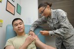 Airman 1st Class Abby Roetzel, 359th Medical Group, Immunization Clinic, independent vaccine technician, immunizes Airman 1st Class Danny Tjhin, July 29, 2015, at the Joint Base San Antonio-Randolph.  Technicians are trained to administer required/recommended immunizations per the Department of Defense (DoD), Centers for Disease Control and Prevention (CDC) and Advisory Committee on Immunizations Practices (ACIP) guidelines and to maintain/track accurate records of immunizations provided.  (U.S. Air Force photo by Joel Martinez/Released)