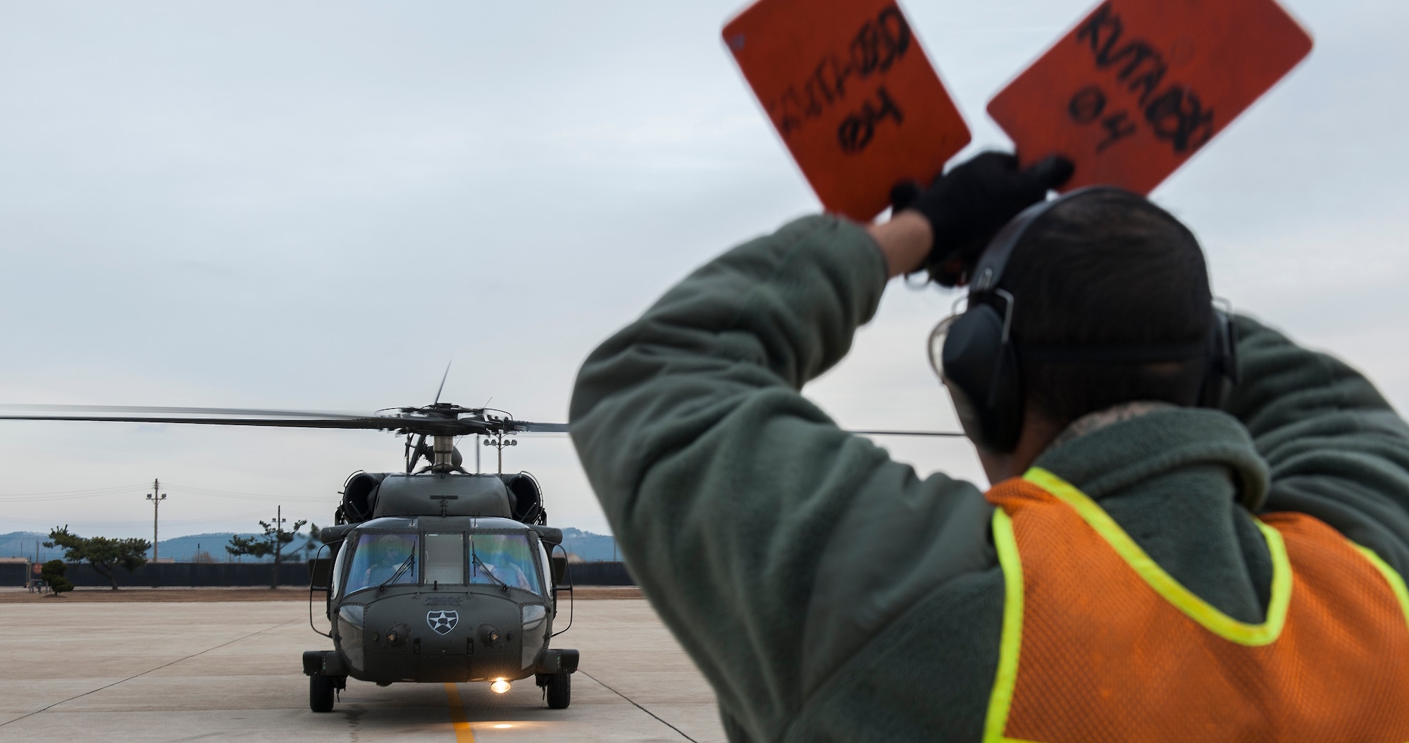 Senior Airman Collin Hubbard, 8th Maintenance Squadron transient assistance crash recovery journeyman, marshals a U8 60 Lima Blackhawk from K16 Airfield, Seoul Air Base, at Kunsan Air Base, Republic of Korea, Jan. 7, 2016. Hubbard works in the maintenance flight, which encompasses multiple duty sections, including a tire shop, aerospace propulsion, crash damage, aircraft recovery and phase. (U.S. Air Force photo by Staff Sgt. Nick Wilson/Released)