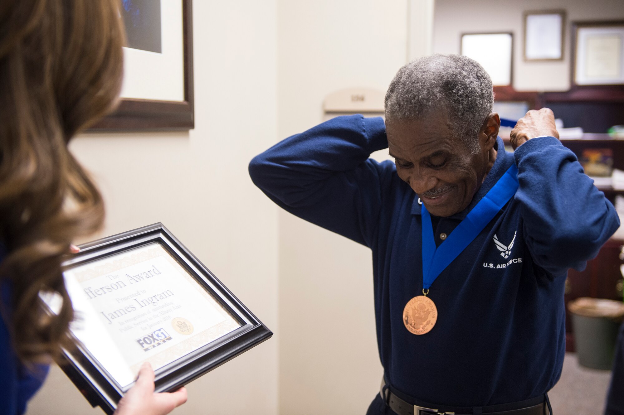 Retired U.S. Air Force Chief Master Sgt. James Ingram, 23d Wing retiree activities office director, places his Jefferson Award medal around his neck, Jan. 12, 2016, at Moody Air Force Base, Ga. An anonymous friend submitted a package on Ingram’s behalf to the committee. (U.S. Air Force photo by Senior Airman Ceaira Tinsley/Released)