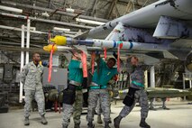 Senior Airmen Dion Smith, Caleb Laurent and Nathan Durland, 25th Aircraft Maintenance Unit weapons load crew, work together to upload a practice sidewinder air-to-air missile to an A-10 Thunderbolt II during the quarterly weapons loading competition on Osan Air Base, Republic of Korea, Jan. 8, 2016. The event added an element of competition to a qualification test for the technicians; crews completed a written test and a practical demonstration of skill within a fixed amount of time to maintain mission-readiness status. (U.S. Air Force photo/Staff Sgt. Amber Grimm/released)