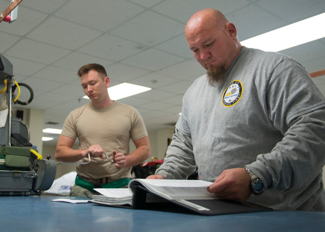 U.S. Air Force Airman 1st Class Eric Hedgepeth, an egress systems journeyman assigned to the 1st Maintenance Squadron, removes a panel from a T-38 Talon seat, while Jason Clem, an aircraft mechanic from M1 Support Services, reads technical orders at Langley Air Force Base, Va., Jan. 8, 2016. Aircrew egress systems specialists also handle and maintain explosive devices used to operate ejection seats, escape hatches and escape capsules. (U.S. Air Force photo by Staff Sgt. J.D. Strong II)
