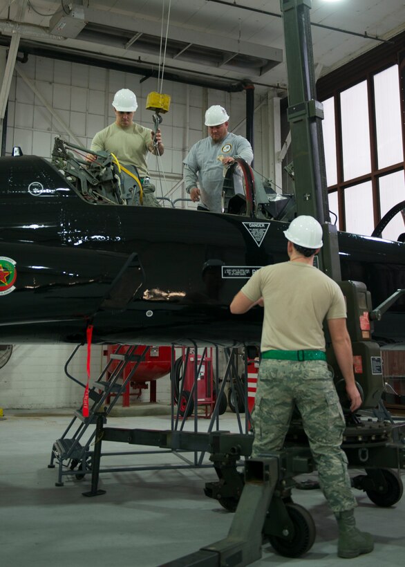 U.S. Air Force Staff Sgt. Kirby Croker and Airman 1st Class Eric Hedgepeth, egress systems technicians assigned to the 1st Maintenance Squadron, assist Jason Clem, an aircraft mechanic from M1 Support Services, to remove a seat from a T-38 Talon at Langley Air Force Base, Va., Jan. 8, 2016. The Talon seat was being removed for annual changes. (U.S. Air Force photo by Staff Sgt. J.D. Strong II) 