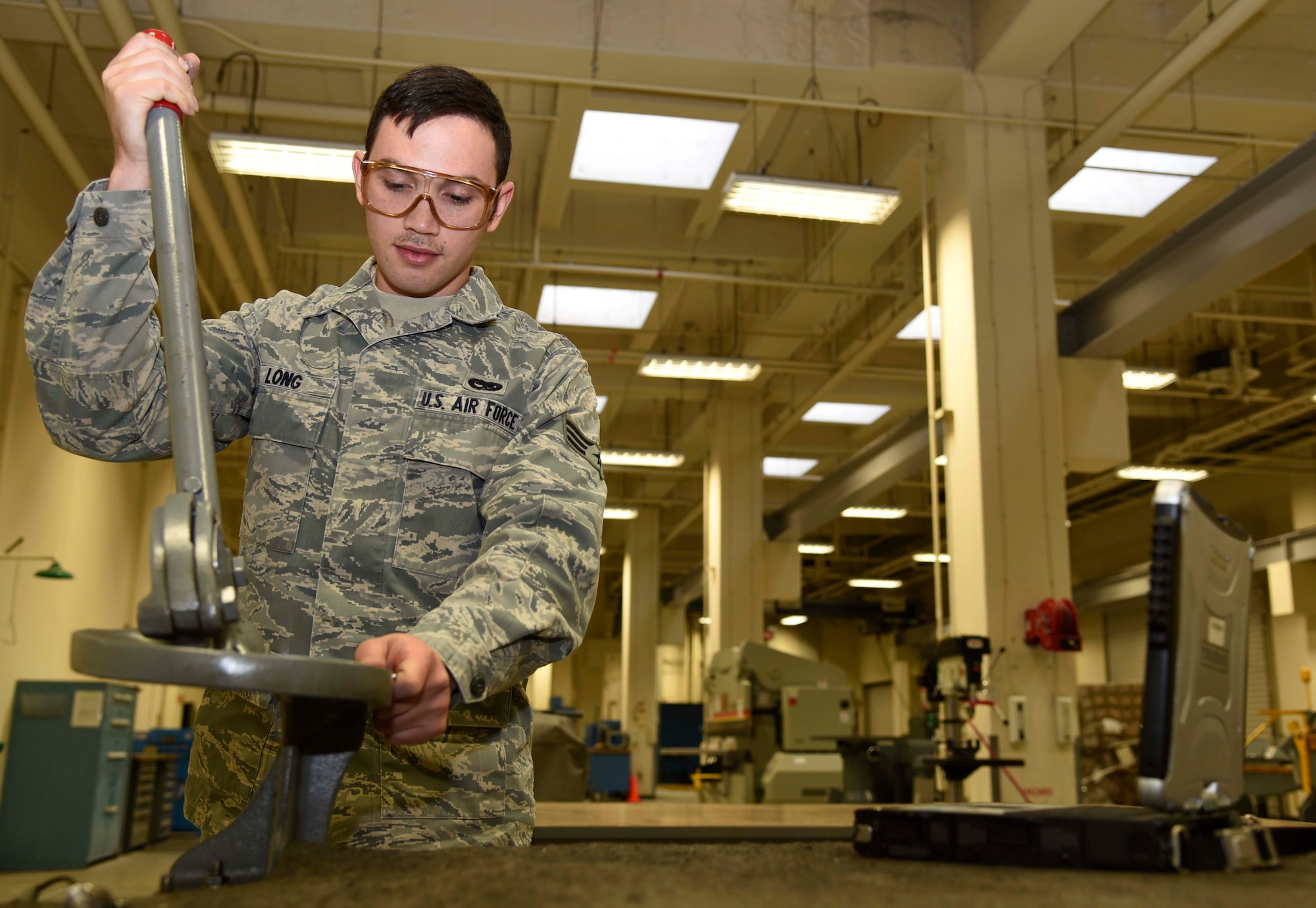 U.S. Air Force Senior Airman Charlton Long, an aircraft structural maintenance journeyman with the 35th Maintenance Squadron, cuts metal at Misawa Air Base, Japan, Jan. 11, 2016. To quickly cut into a metal portion, Long used a throatless shear due to its swift set-up and application. A throatless shear is a tool used to slice straight, curved or irregular cuts in metals. Pieces like this are then used as replacement parts on physically damaged F-16 Fighting Falcons. (U.S. Air Force photo by Airman 1st Class Jordyn Fetter)