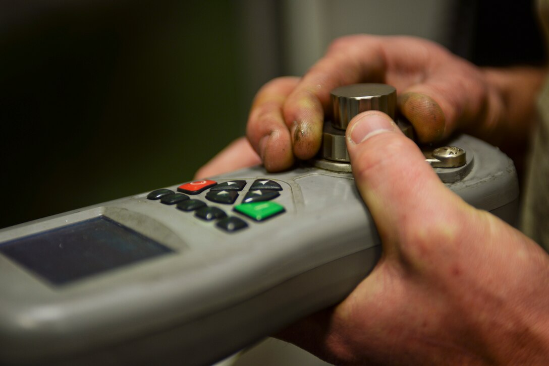 Senior Airman Tyler Jones, 28th Maintenance Squadron metals technician, controls a Haas VF 4 remote to make slight corrections to the position of the base at the machine at Ellsworth Air Force Base, S.D., Jan. 6, 2016. Read on an X, Y and Z axis, the machine is able to cut from side to side and up and down. The metals flight creates aircraft parts that cannot be ordered through a supplies list. (U.S. Air Force photo by Airman Sadie Colbert/Released)