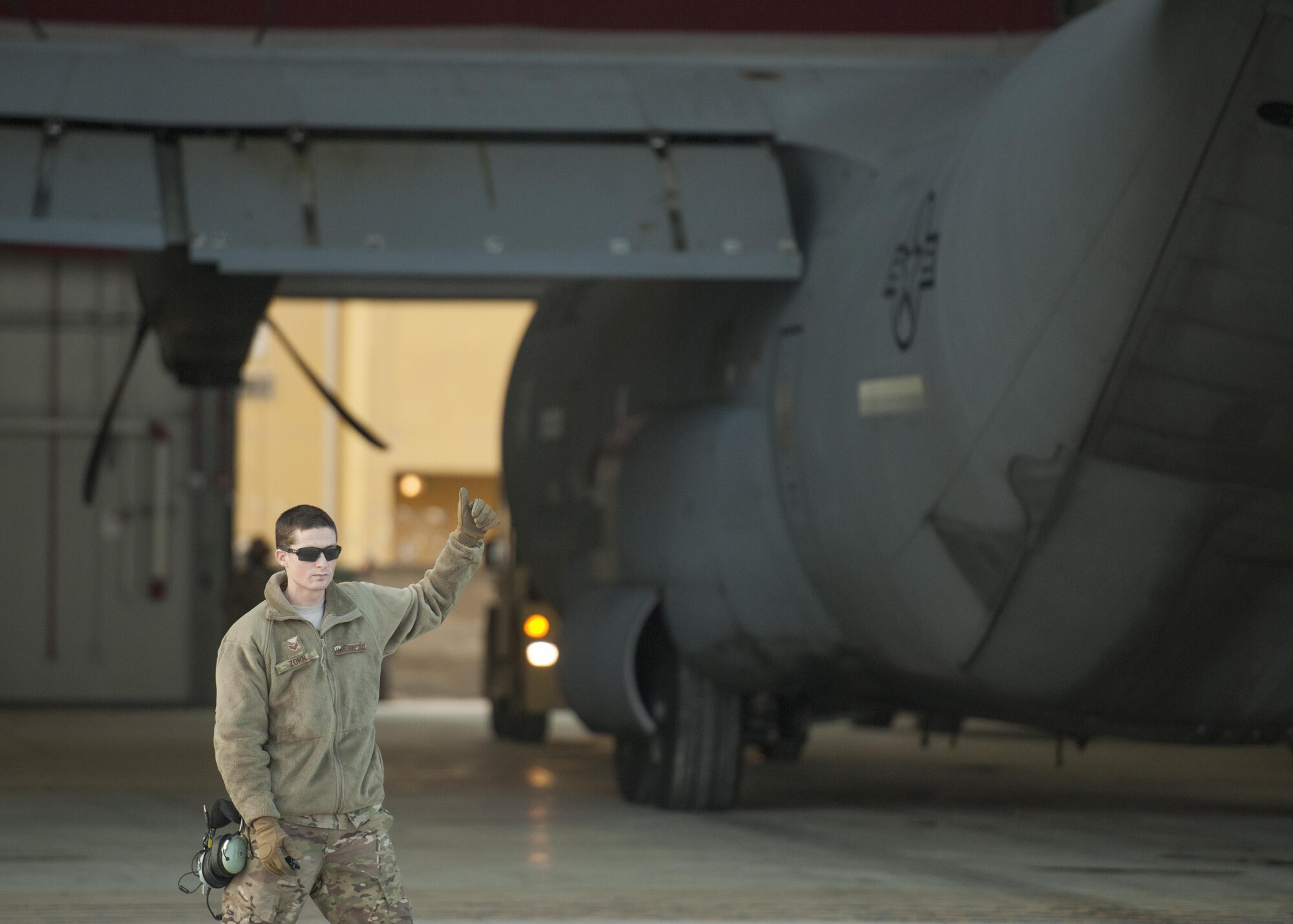 Senior Airman James Zorn, 455th Expeditionary Aircraft Maintenance Squadron crew chief, guides a C-130J Super Hercules as it is towed to the flightline for an engine test at Bagram Airfield, Aghanistan, Jan. 12, 2016. The aircraft, used in support of Operation Freedom's Sentinel and NATO's Resolute Support mission, was housed in a hangar while it had an engine replaced. (U.S. Air Force photo/Tech. Sgt. Robert Cloys) 