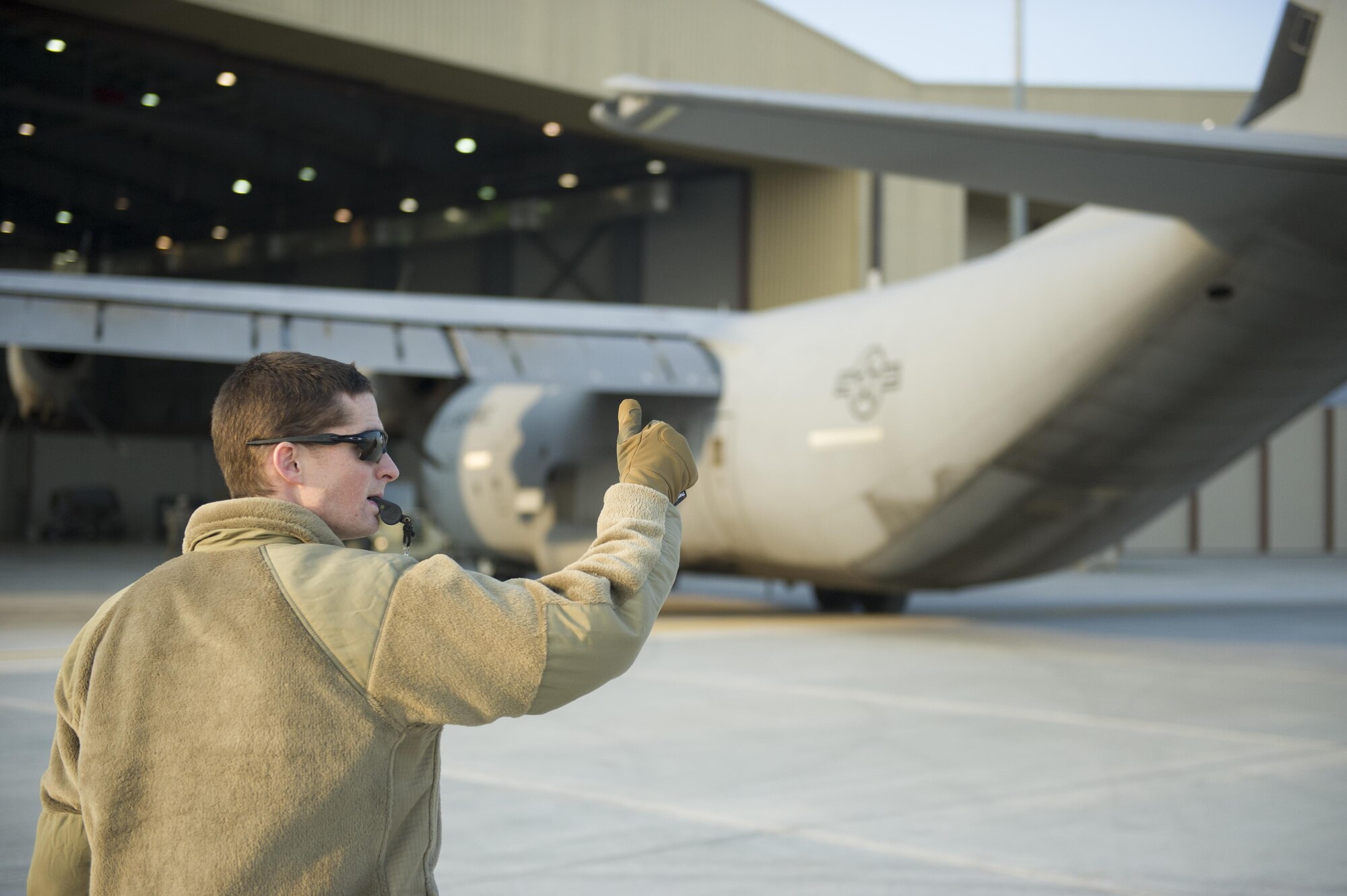 Senior Airman James Zorn, 455th Expeditionary Aircraft Maintenance Squadron crew chief, guides a C-130J Super Hercules as it is towed to the flightline for an engine test at Bagram Airfield, Aghanistan, Jan. 12, 2016. The aircraft, used in support of Operation Freedom's Sentinel and NATO's Resolute Support mission, was housed in a hangar while it had an engine replaced. (U.S. Air Force photo/Tech. Sgt. Robert Cloys) 