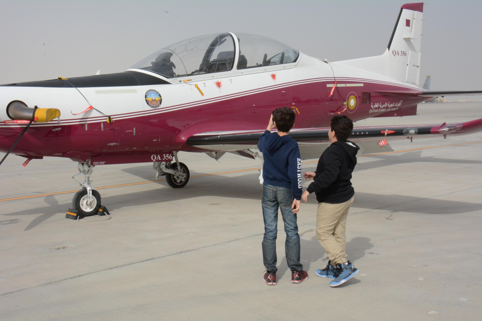 Two children take photos of a PC-21 with one of their cell phones during the annual Flight Line Fest at Al Udeid Air Base, Qatar, Jan. 10. The plane is used to train Qatar Emiri Air Force pilots and flies at a max speed of 317 knots. Flight Line Fest is a joint partnership between the 379th Air Expeditionary Wing and QEAF held to foster relations between Qatar and the United States. (U.S. Air Force photo by Tech. Sgt. James Hodgman/Released)