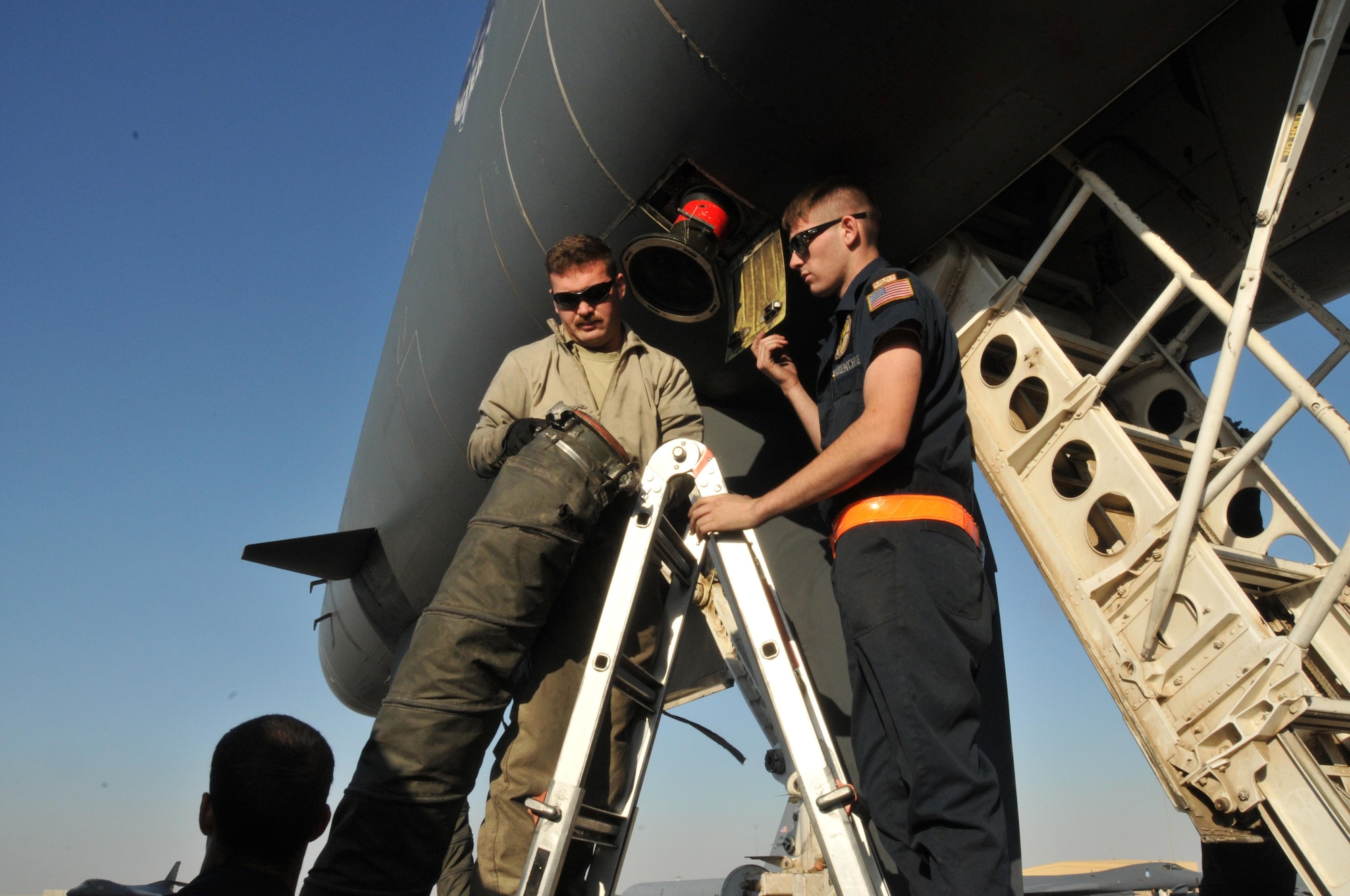 Senior Airman Brandon Wilkins (left) and Airman 1st Class Jacob Shores (right), hook up power and air to a B-1 B Lancer Jan. 11 at Al Udeid Air Base, Qatar. During a post-flight inspection, maintainers hook up both power and air which allows the jet to stay cool while it receives gas. Wilkins and Shores are maintainers deployed from Ellsworth Air Force Base, South Dakota. (U.S. Air Force photo by Tech. Sgt. Terrica Y. Jones/Released)