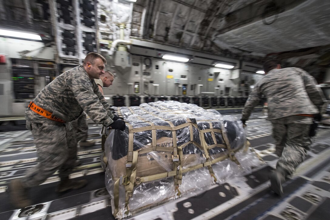 U.S. Air Force airmen load cargo onto a C-17 Globemaster III aircraft at Al Udeid Air Base, Qatar, in support of Operation Resolute Support, Jan. 13, 2016. The airmen are assigned to the 8th Expeditionary Air Mobility Squadron. U.S. Air Force photo by Staff Sgt. Corey Hook