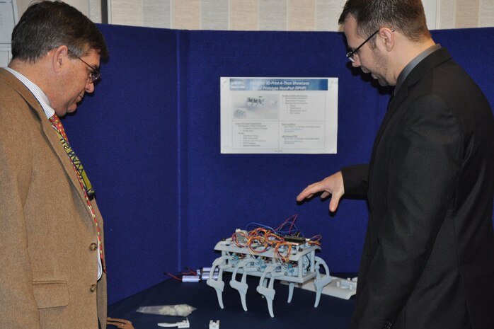 Jason Phillips (right), an NSWCDD engineer, demonstrates the Rapid Prototype HexaPod Robot for NSWCDD Technical Director Dennis McLaughlin. It was showcased at the December Print-A-Thon. 