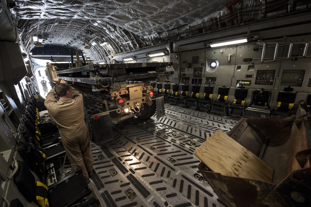 U.S. airmen use hand signals while loading a truck into an Air Force C-17 Globemaster III in Afghanistan, Jan. 13, 2016. U.S. Air Force photo by Staff Sgt. Corey Hook