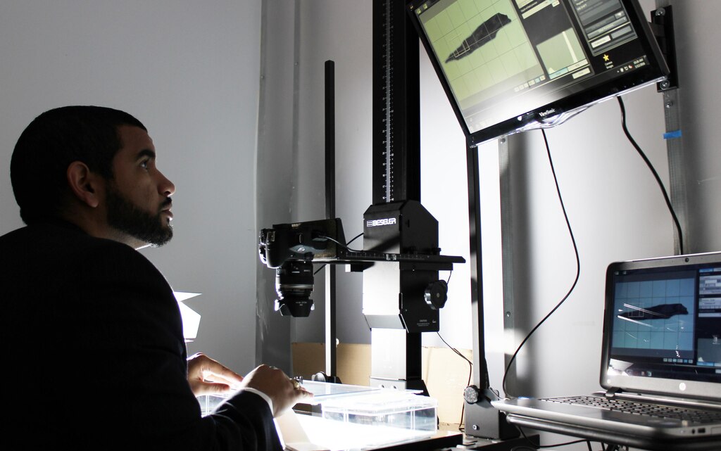 Ignacio Reyes, archaeological laboratory technician, works on photographing artifacts at the Veterans Curation Program open house in Alexandria, Virginia, Jan. 12, 2016. The VCP provides employment and vocational training for recently separated veterans using archaeological collections administered by the U.S. Army Corps of Engineers. Reyes was an infantryman with the Army from 2005 to 2013 in which he deployed to Iraq and completed a multinational force and observers tour in Egypt. Veterans working in the Alexandria laboratory are being trained in data entry, report writing, photography, and scanning technologies. (U.S. Army photo by Sarah Gross) 

Photo was cropped and altered for contrast and brightness.