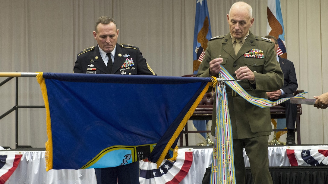 Command Sgt. Maj. William B. Zaiser holds the U.S. Southern Command flag while U.S. Marine Corps Gen. John F. Kelly attaches a Meritorious Unit Award streamer during the change of command ceremony at SOUTHCOM headquarters in Doral, Fla., Jan. 14, 2016. U.S. Navy Adm. Kurt W. Tidd is the new SOUTHCOM commander succeeding U.S. Marine Corps Gen. John F. Kelly.