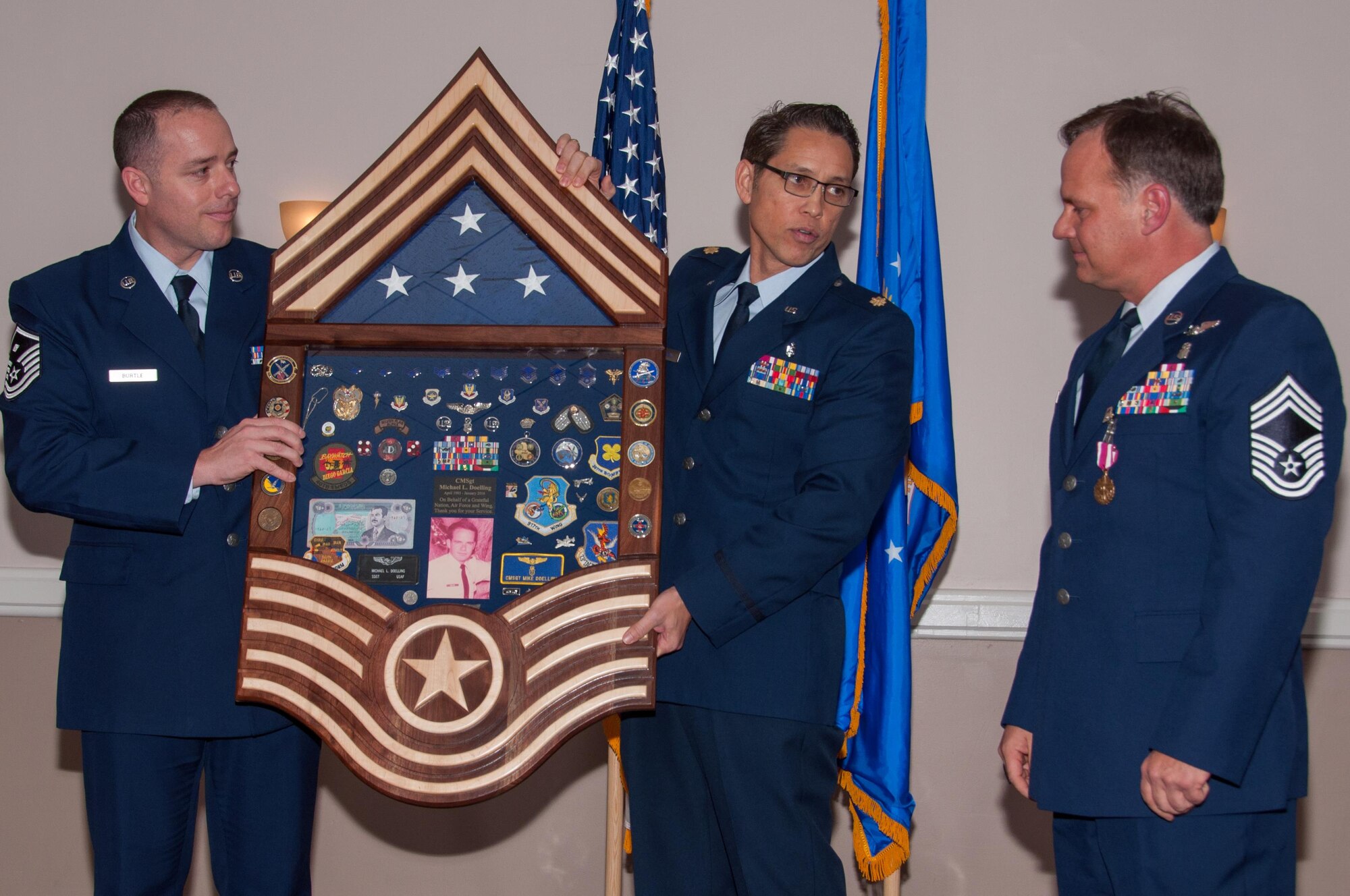 U.S. Air Force Master Sgt. Edward Burtle and Maj. Joe Oswald, both assigned to the 307th Medical Squadron, present Chief Master Sgt. Michael Doelling a shadow box commemorating his thirty years in the Air Force at a retirement ceremony on Jan. 09, 2016, Barksdale Air Force Base, La. Doelling was the superintendent of medical services and readiness planner for the 307th Medical Squadron, 307th Bomb Wing on Barksdale. (U.S. Air Force photo by Master Sgt. Laura Siebert/Released)