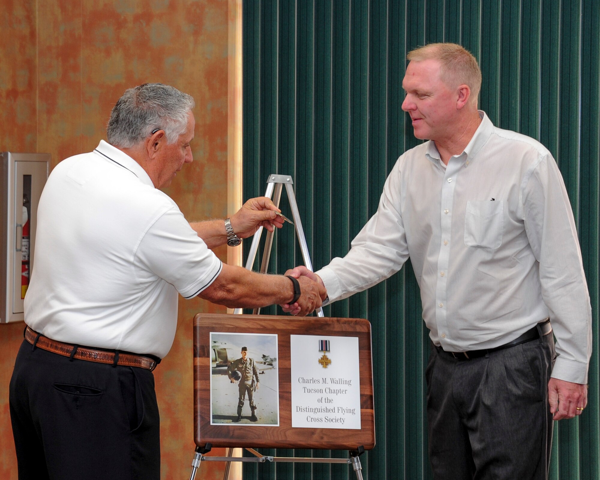 Martin Lenzini, President of the Tucson Chapter of the Distinguished Flying Cross Society presents Jeff Walling with a coin during a luncheon at Davis-Monthan Air Force Base, Ariz., Jan. 13, 2016.  Lenzini unveiled a plaque commemorating the renaming of the Tucson Chapter honoring Walling’s father, U.S. Air Force Lt. Col. Charles M. Walling, who died during a mission over Vietnam in 1966.  (U.S. Air Force photo by Senior Airman Chris Massey/Released)